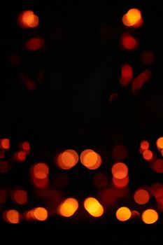 Abstract image of vibrant orange bokeh lights against a deep black background suggesting warmth and energy.