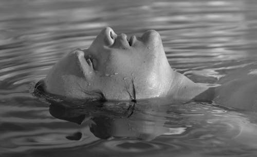 Grayscale Photo of a Pretty Woman Swimming 