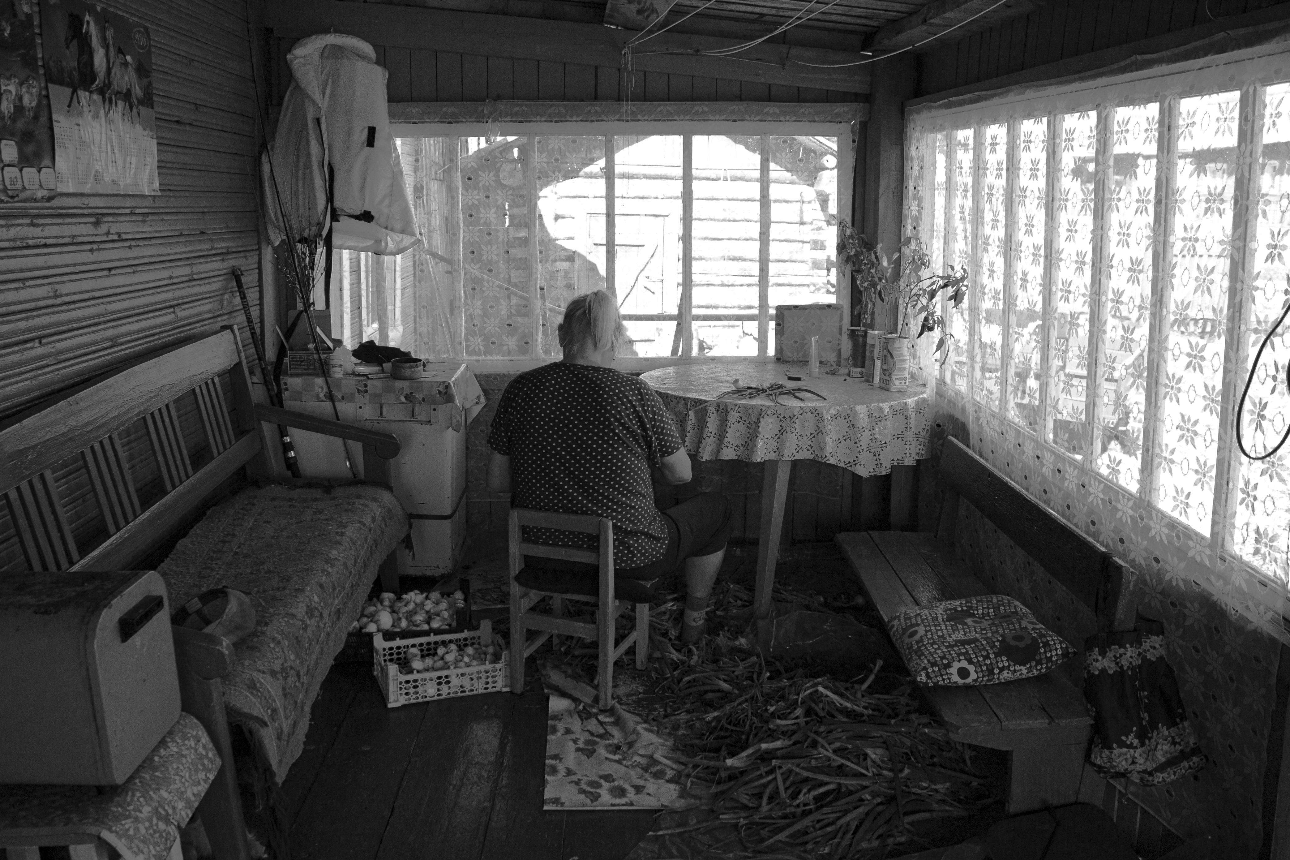 Grayscale Photo of a Person Sitting on a Small Wooden Chair