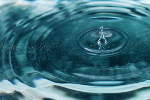 бесплатная Фотография крупным планом капель воды, падающих на спокойную воду Стоковое фото