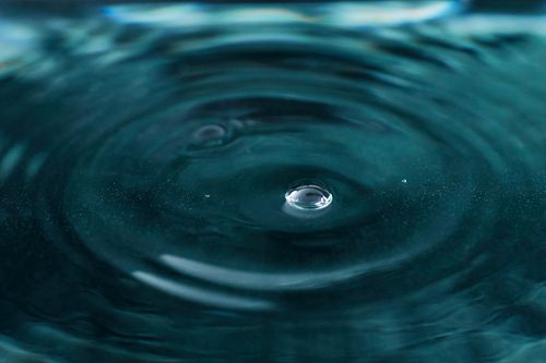 Free Serene close-up of a water droplet creating concentric ripples. Ideal for backgrounds. Stock Photo