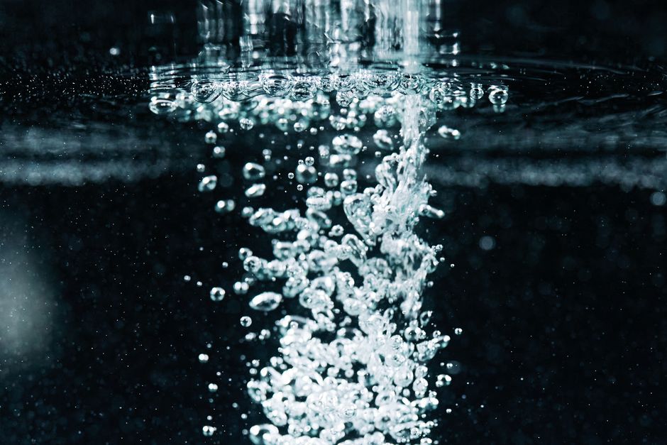 Macro image capturing dynamic bubbles and effervescence in water, showcasing texture and movement.