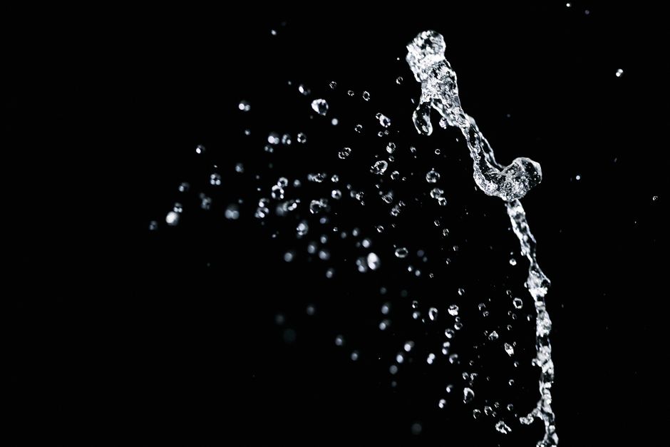 A high-speed capture of water droplets creating a splash on a dark background.