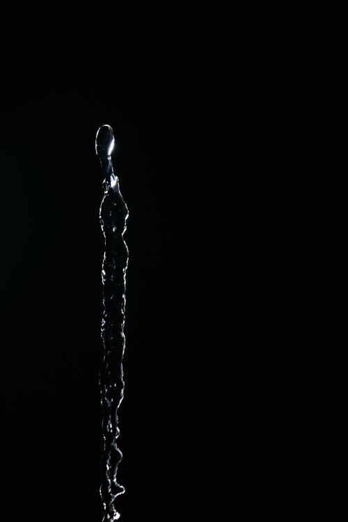 Free Captivating high-speed capture of vertical water splash against dark background. Stock Photo
