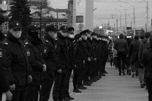 Free Police officers in uniform wearing masks stand lined up in a city street, enforcing order. Stock Photo