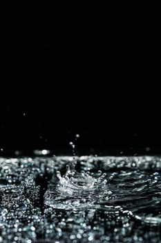 Artistic capture of a water splash on a reflective surface, set against a black background.