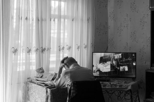Free Senior adult sitting at home desk, contemplating, watching monitor in black and white. Stock Photo