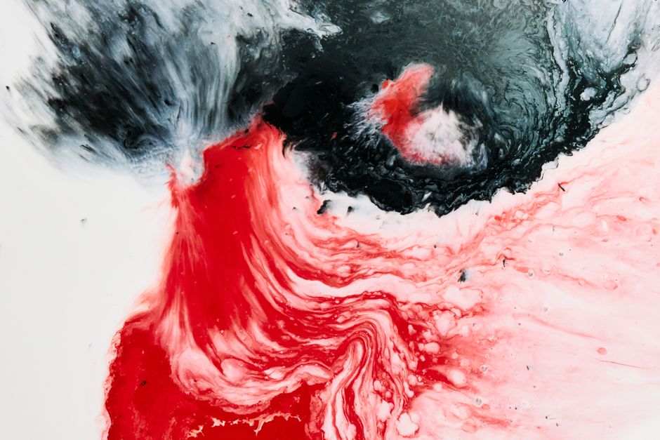 Dynamic acrylic pouring artwork with swirling red and black tones creating vibrant abstract patterns.