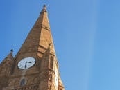 晴朗的蓝天下，哥特式教堂的塔楼带着时钟，从低角度拍摄