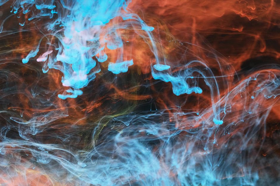 Vivid abstract artwork of swirling blue and orange ink diffusion creating intricate patterns.