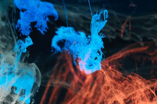 Dynamic image of blue and orange ink swirling in water, showcasing vibrant colors and abstract textures.