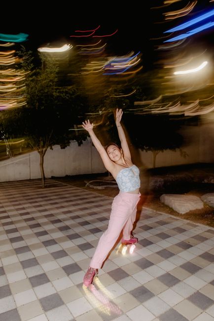 A joyful woman elegantly roller skates on a city street at night, capturing movement and energy.