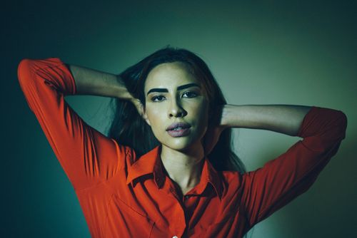 Free Striking portrait of a woman in a red shirt posing confidently in a studio. Stock Photo