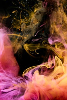 Abstract high-speed capture of swirling pink and yellow smoke with dynamic hues and textures.