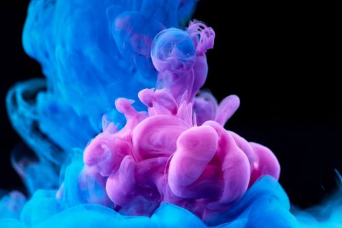Free A mesmerizing mix of blue and pink ink swirling in water, captured in high-speed photography. Stock Photo