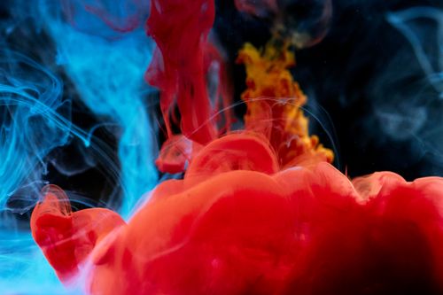 Free Abstract image of vibrant red, blue, and yellow ink swirling in water, creating a dynamic composition. Stock Photo