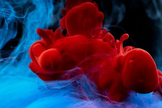 Abstract mixture of red and blue ink swirling fluidly in water. Vibrant and colorful visual effect.