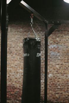 Punching bag suspended indoors against a rustic brick wall for fitness and training.