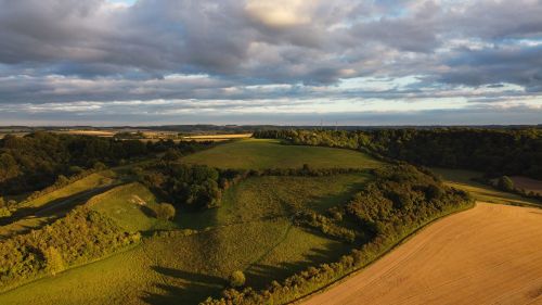 Free Explore the rolling fields and lush greenery of rural England, captured in a stunning aerial view under dramatic cloud cover. Stock Photo