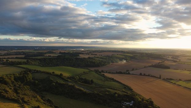 Stunning aerial view of Sharpenhoe countryside with lush fields and dramatic clouds during sunset.