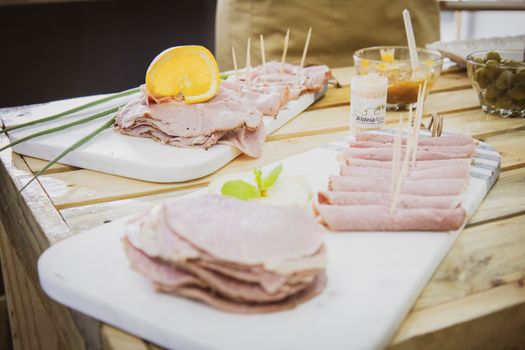 Close-up of a ham appetizer platter with orange garnish and toothpicks for serving.