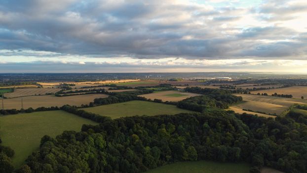 Aerial shot of lush green fields and forests in Sharpenhoe, England under a cloudy sky.