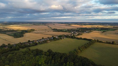 Free Scenic aerial view of English farmland and village under a cloudy sky at sunset. Stock Photo