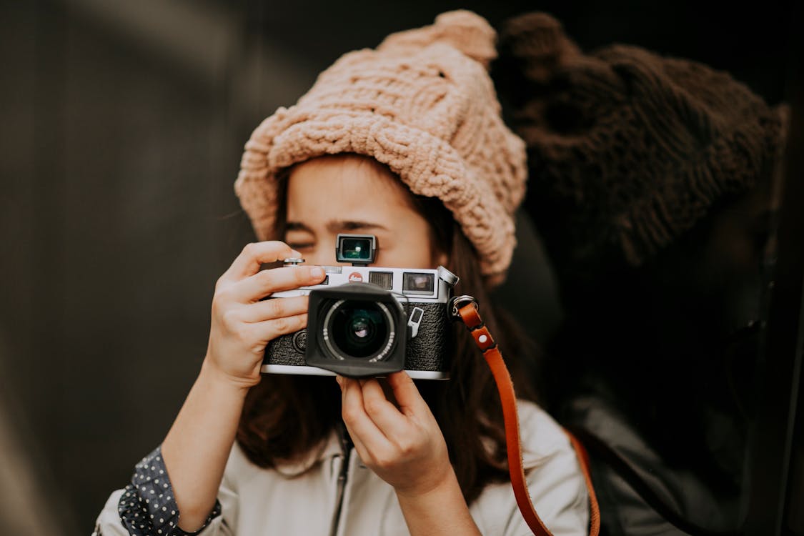 Girl in pink knitted hat taking photo