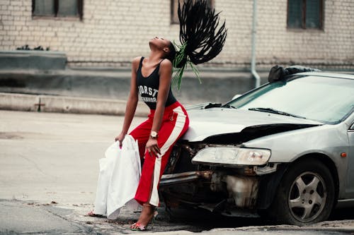 Wanita Dengan Tank Top Hitam Duduk Di Depan Mobil