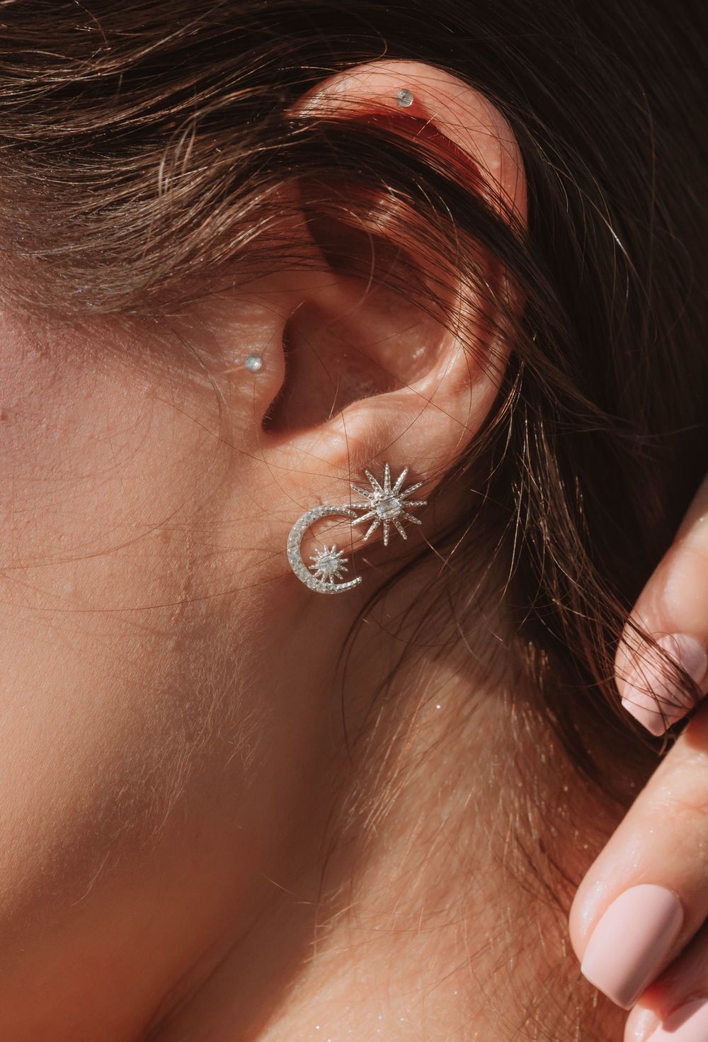 Star-and-moon earring on a pierced ear
