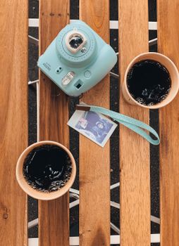 Instant camera with coffee cups on a wooden table, capturing a cozy moment in Kyiv, Ukraine.