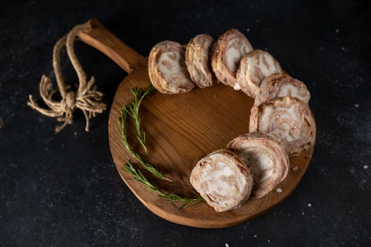 Close-up of artisan meat rolls on a rustic wooden board with rosemary sprigs. Perfect for culinary enthusiasts.