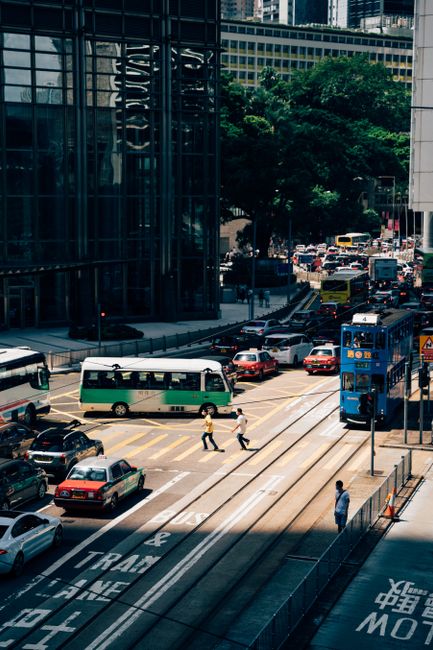 Vibrant city street with cars, buses, and pedestrians in downtown Hong Kong.