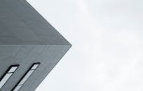 现代建筑立面以极简主义视角呈现，光滑的窗户映衬着苍白的天空