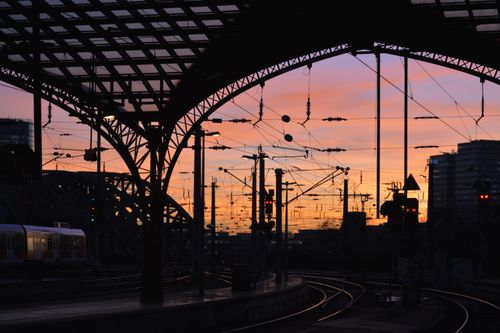 Free Dramatic sunset view of a railway station silhouette in Germany showcasing structural elegance and evening hues. Stock Photo