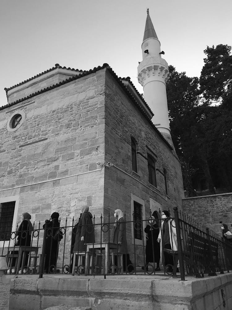 Grayscale Photo Of People Walking Near Brick Building