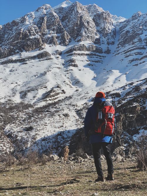 Free A lone hiker with a backpack gazes at the snowy mountains in Dokan, Iraq. Stock Photo