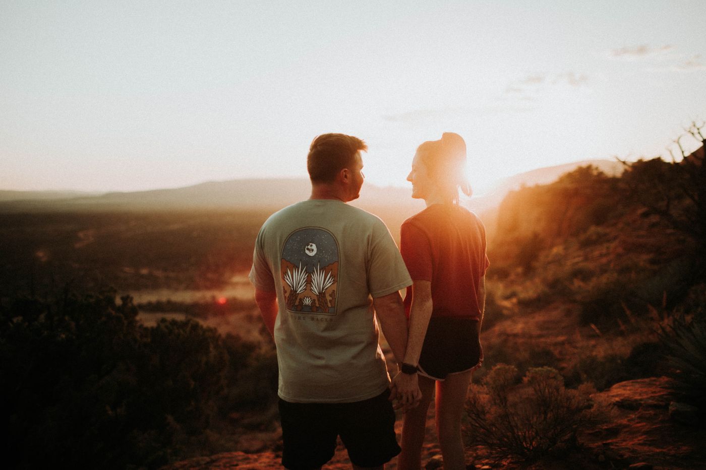 Couple holding hands during golden hour among Sedona’s red rocks