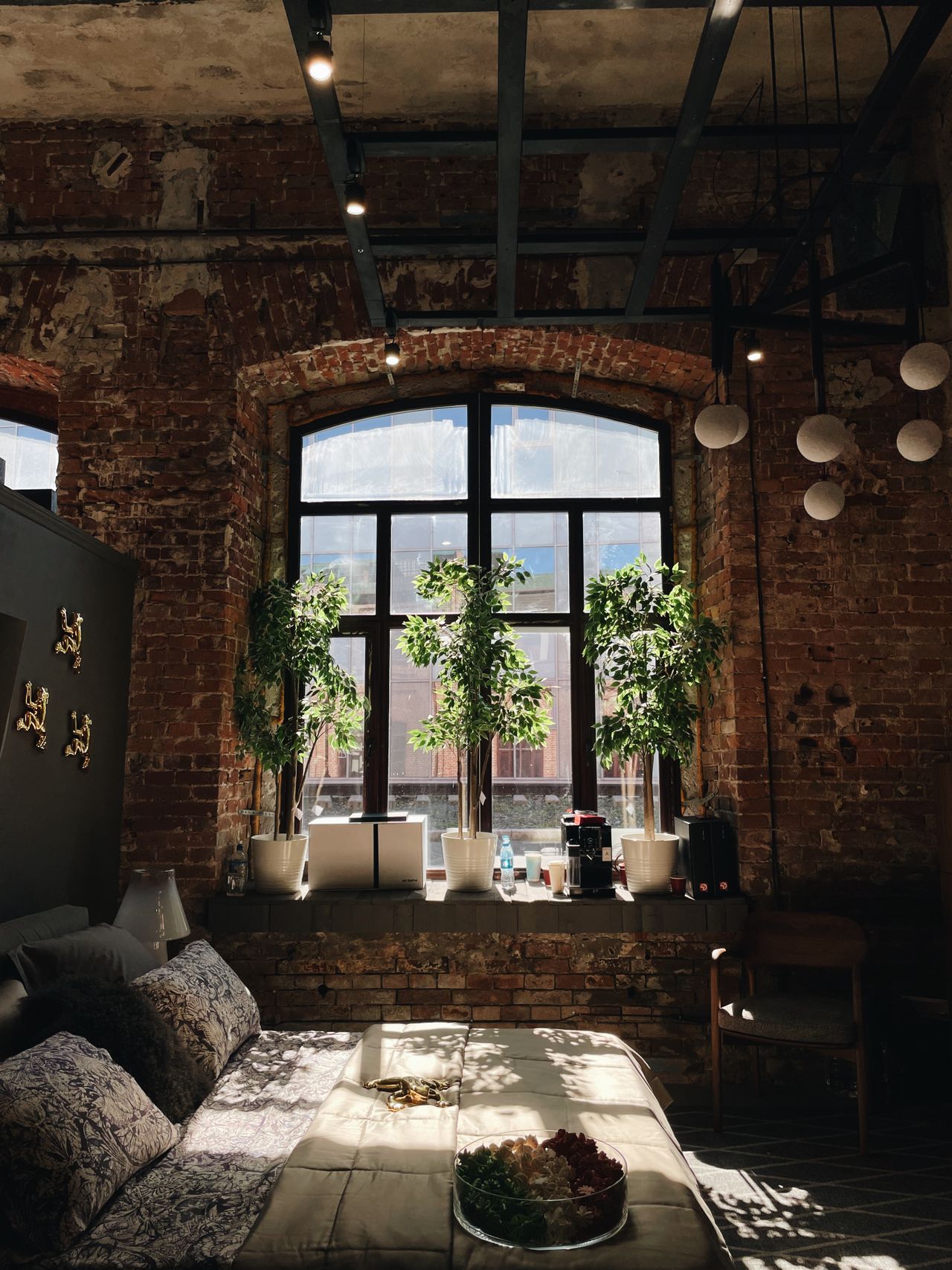 Raw brick loft interior with tall arched factory windows and steel ceiling beams