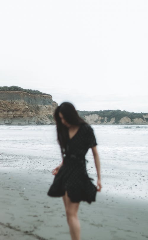 Free A Woman in Black Dress Standing on Beach Stock Photo