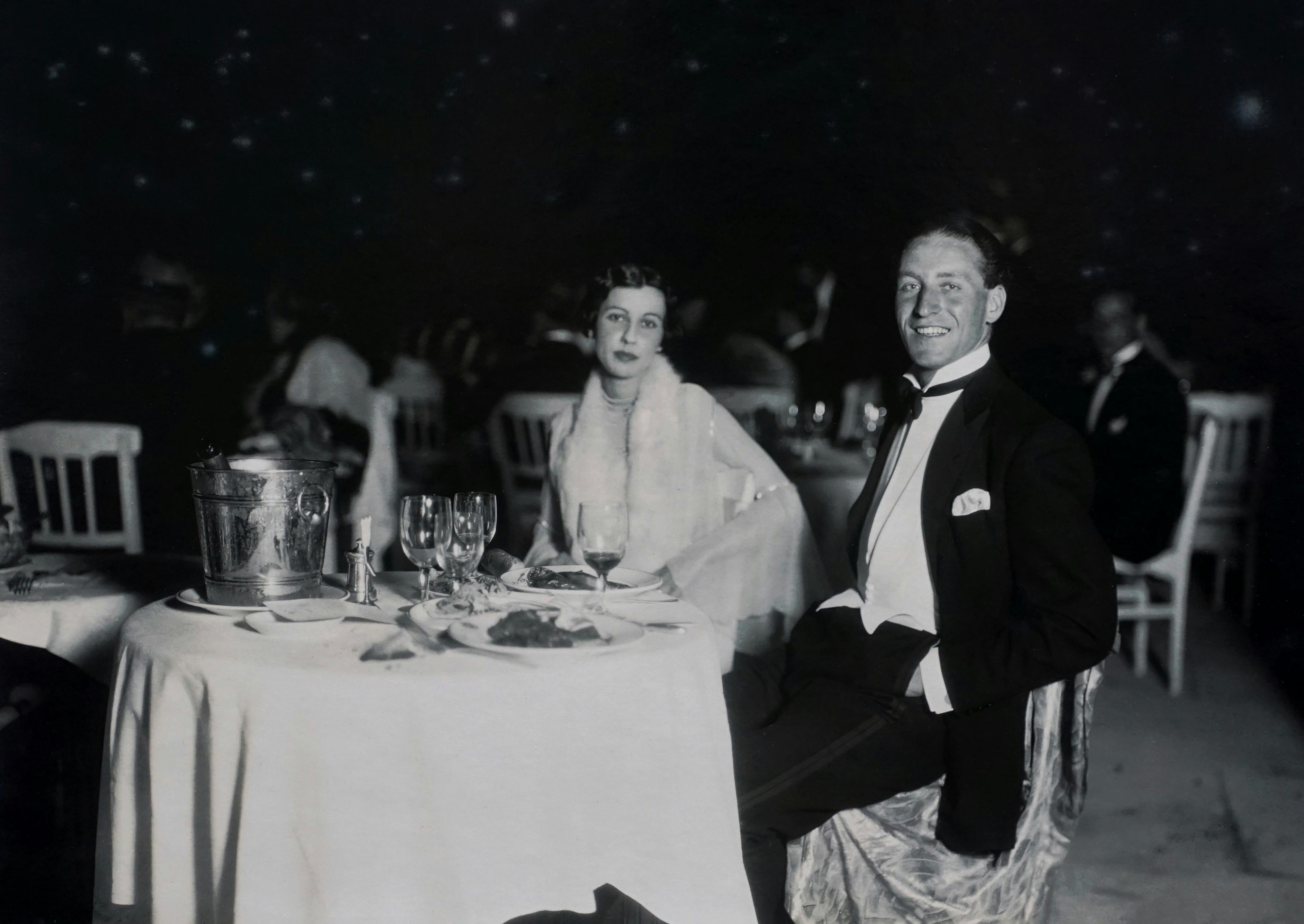Vintage black and white photo of an elegant couple dining at a formal event.