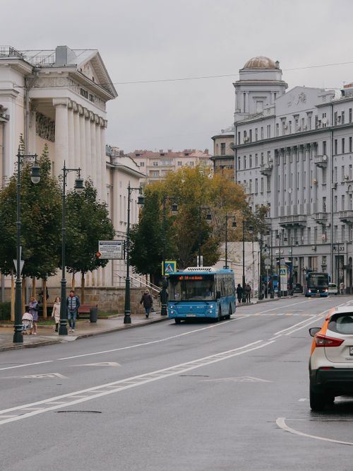 Free A city street featuring blue buses, pedestrians, and historic buildings, capturing urban life. Stock Photo