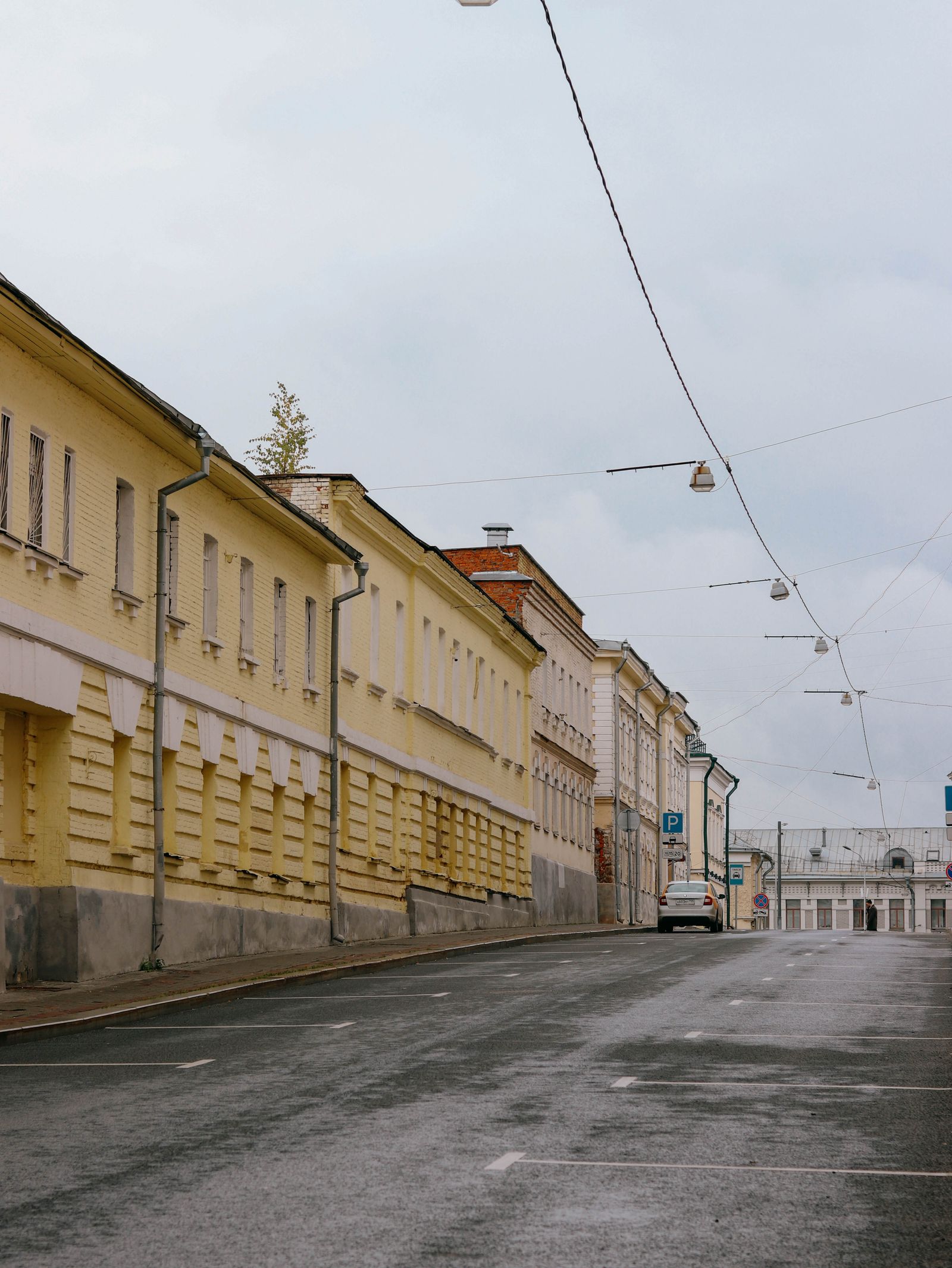 An empty street between long pale buildings, with not a single tree, under a grey sky