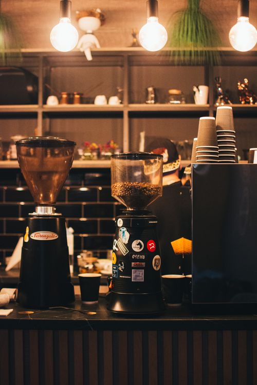 Free Warm coffee shop scene featuring espresso machines and ambient lighting at a stylish counter. Stock Photo