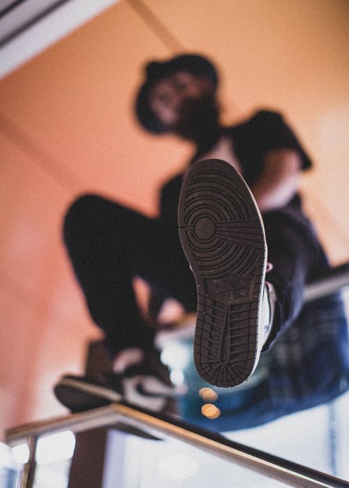 Free A man in casual wear sitting on a glass surface, focus on the shoe sole. Stock Photo