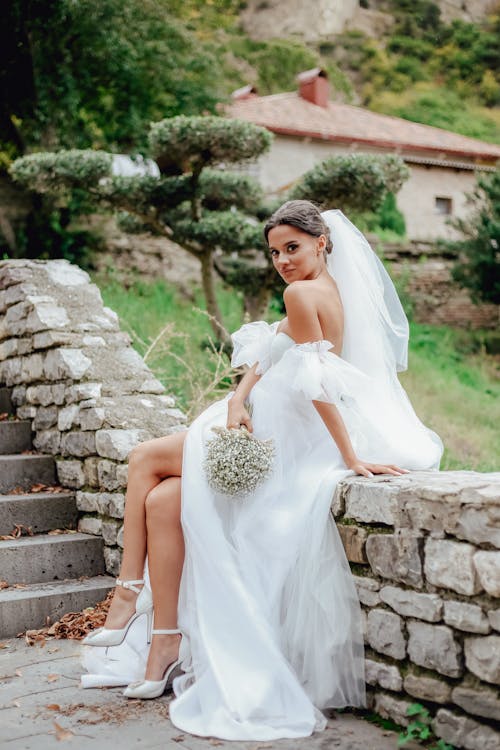 Woman in Bridal Gown Holding Bouquet of Flowers