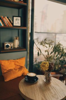 Warm cafe setting with a latte art coffee on a wooden table, offering a cozy, inviting ambiance.