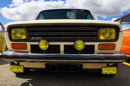 Close-up of a vintage Fiat 147 with yellow headlights at a car show in Brazil.