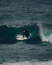 Man in Black Wet Suit Riding White Surfboard on Body of Water