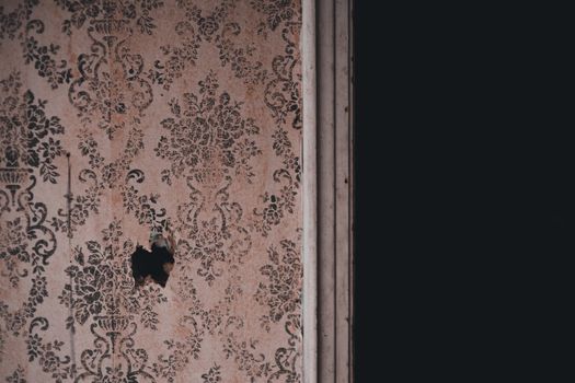 Close-up of an aged floral wallpaper with a small hole, offering a rustic and nostalgic feel.